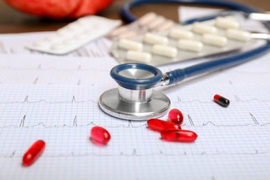 Stethoscope, cardiogram and pills on table. Cardiology service