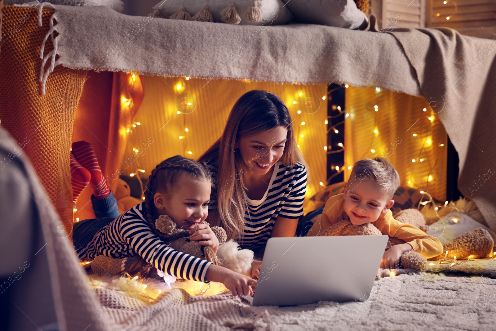 Photo of Mother and her children with laptop in play tent at home