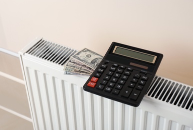 Photo of Heating radiator with calculator and money on color wall