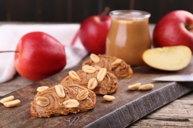 Photo of Pieces of fresh apple with peanut butter on wooden table