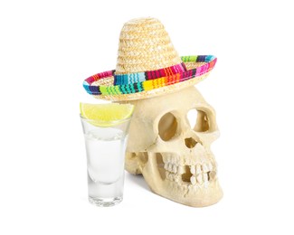 Photo of Mexican sombrero hat, human scull and tequila with lime in glass isolated on white