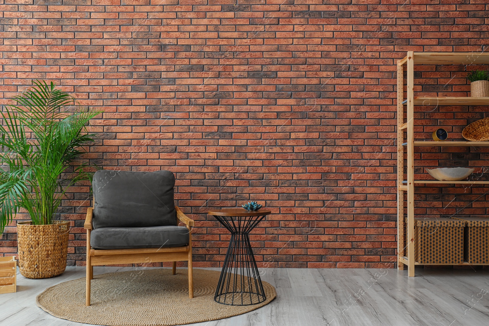 Photo of Modern room interior with stylish grey armchair and potted plant near brick wall