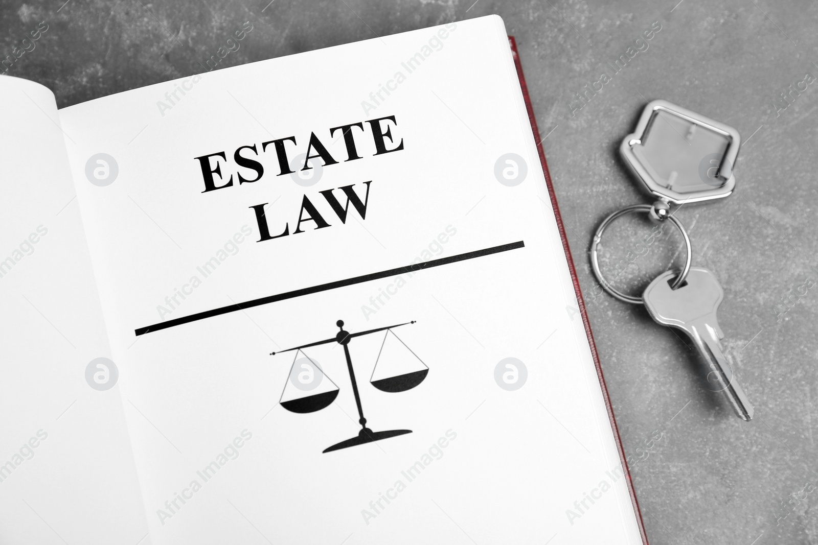 Photo of Book with words ESTATE LAW and house key on grey background, top view