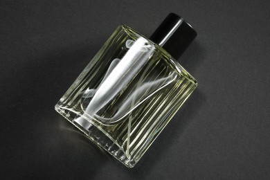 Photo of Luxury men`s perfume in bottle on black background, top view