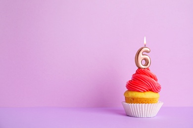 Photo of Birthday cupcake with number six candle on violet background, space for text