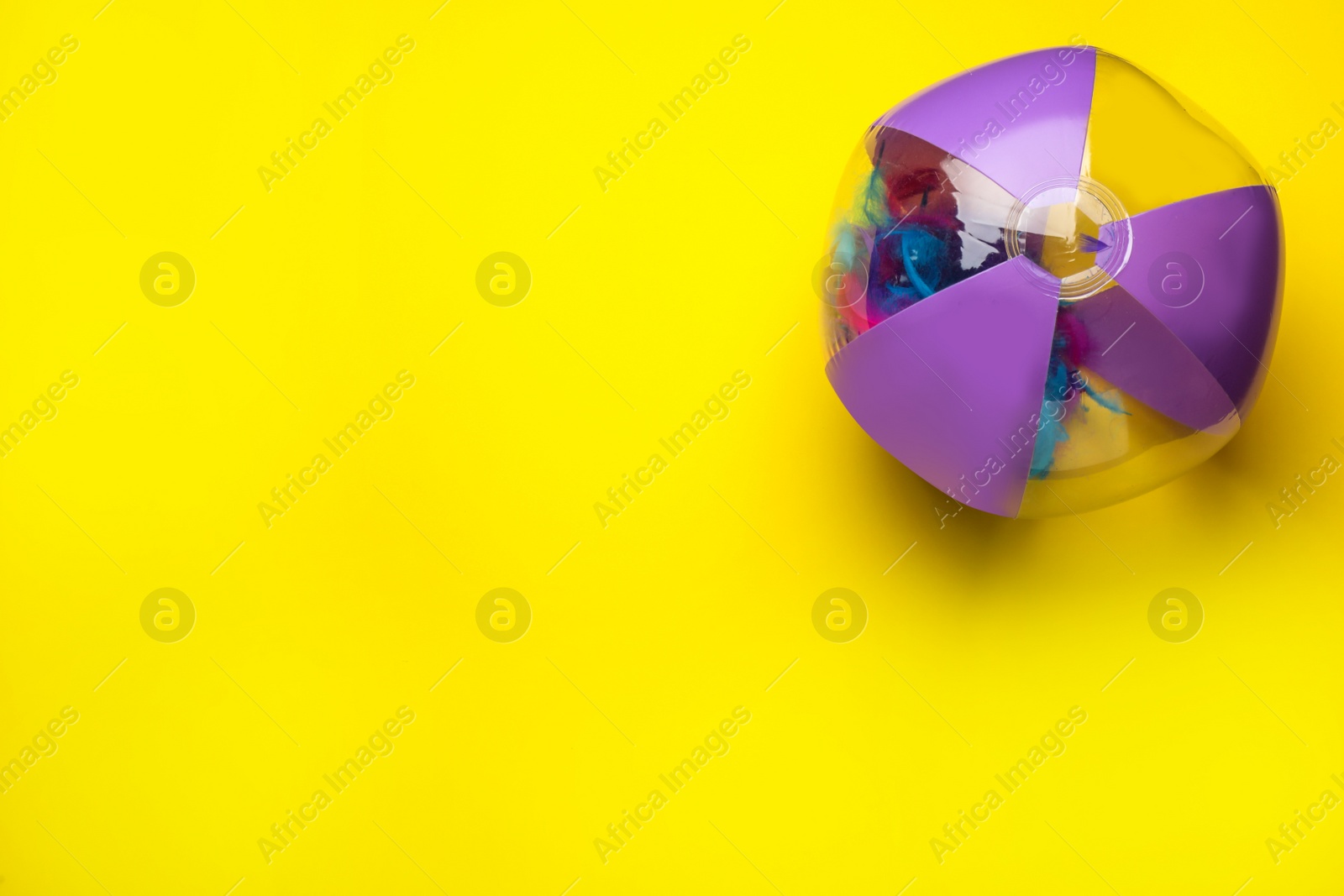 Photo of Bright beach ball on yellow background, top view. Space for text