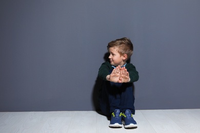 Photo of Depressed little boy sitting on floor indoors. Time to visit child psychologist