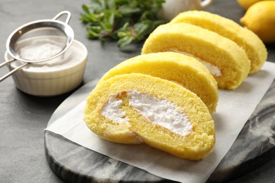 Delicious cake roll with cream filling on grey table, closeup