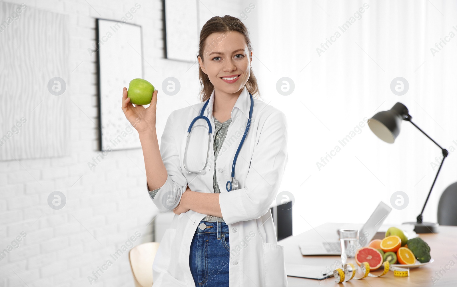 Photo of Nutritionist with fresh apple near desk in office