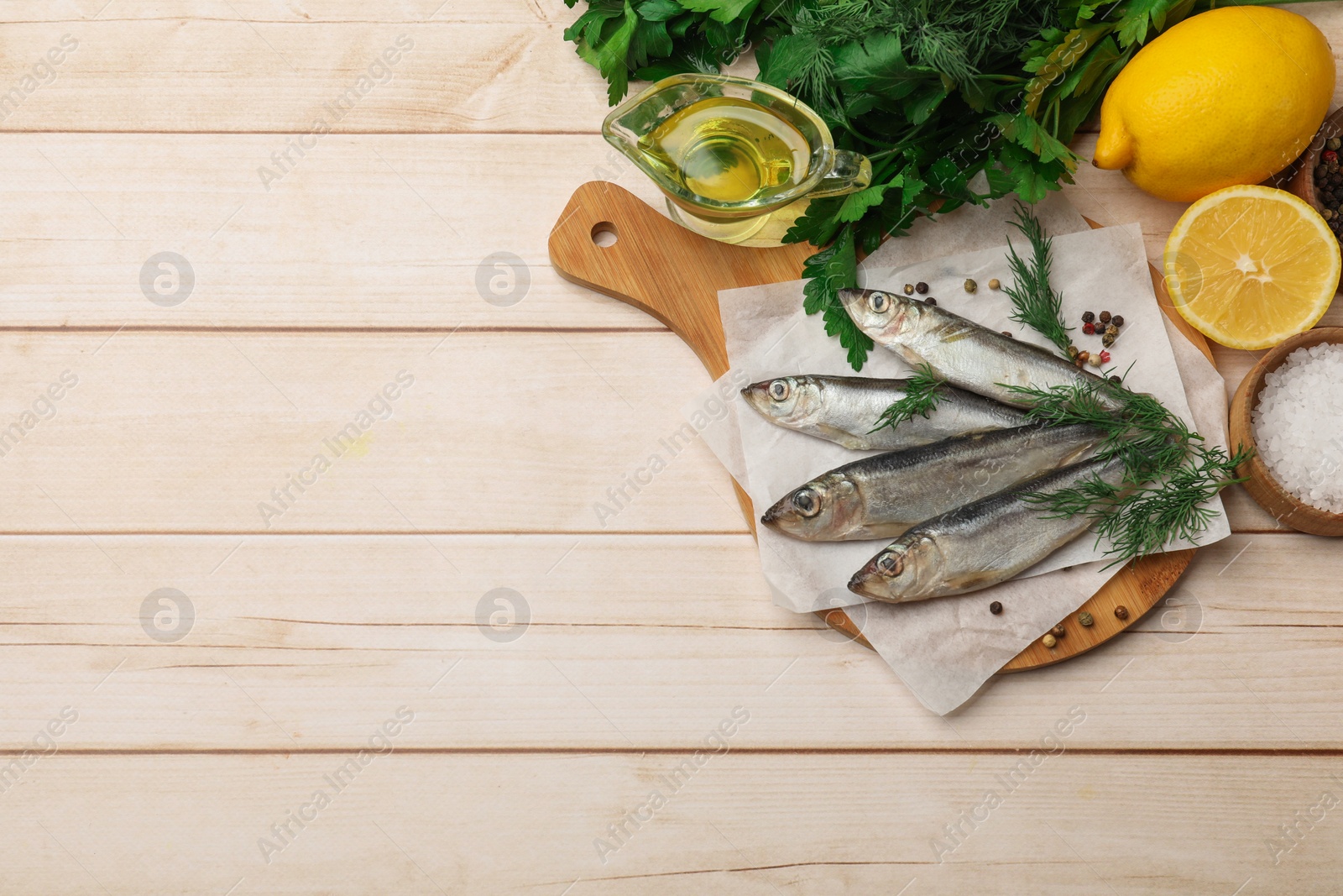 Photo of Fresh raw sprats, peppercorns and dill on light wooden table, top view. Space for text