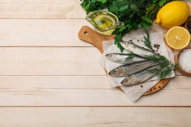 Photo of Fresh raw sprats, peppercorns and dill on light wooden table, top view. Space for text