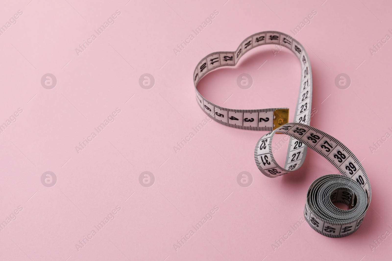 Photo of Measuring tape on pink background, space for text