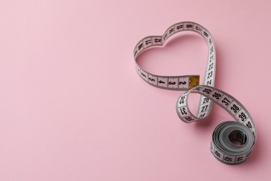 Photo of Measuring tape on pink background, space for text