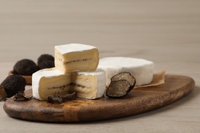 Photo of Delicious cheese and fresh black truffles on white wooden table