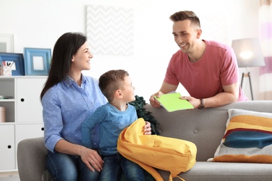 Photo of Young parents helping their little child get ready for school at home