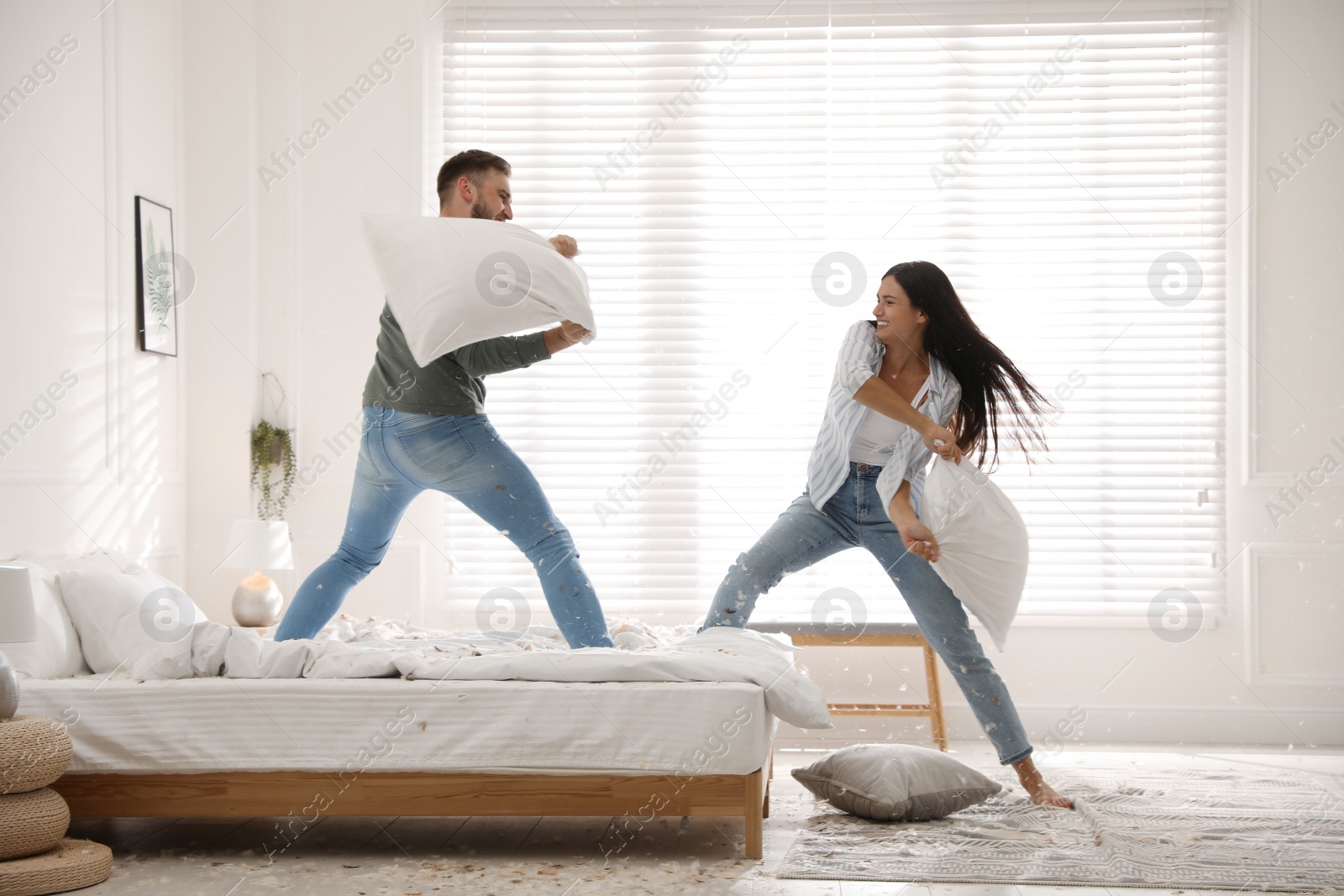 Photo of Happy young couple having fun pillow fight in bedroom