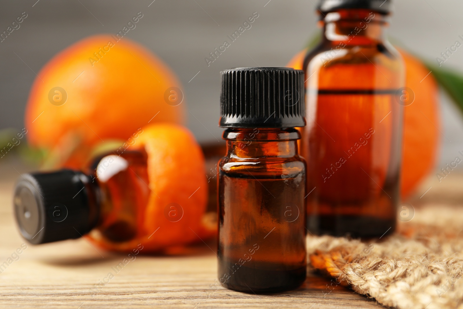 Photo of Bottles of tangerine essential oil on wooden table, closeup