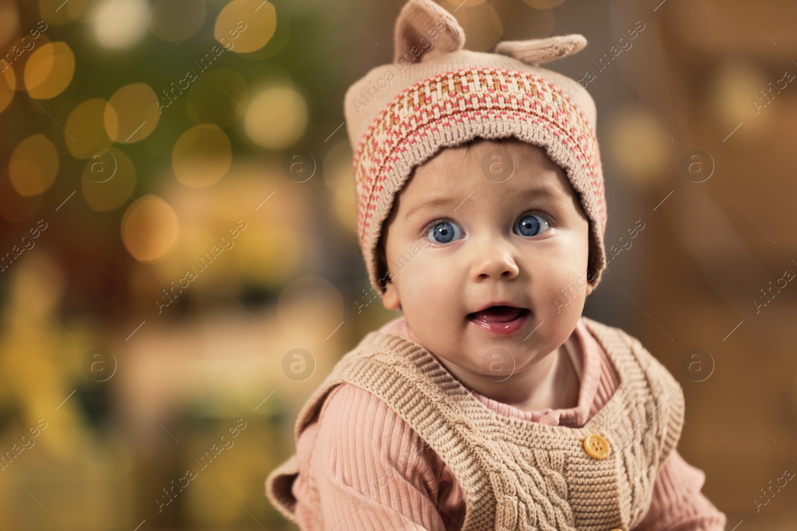 Photo of Cute little baby and blurred Christmas lights on background, space for text. Winter holiday