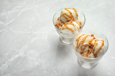 Bowls with caramel ice cream on light background