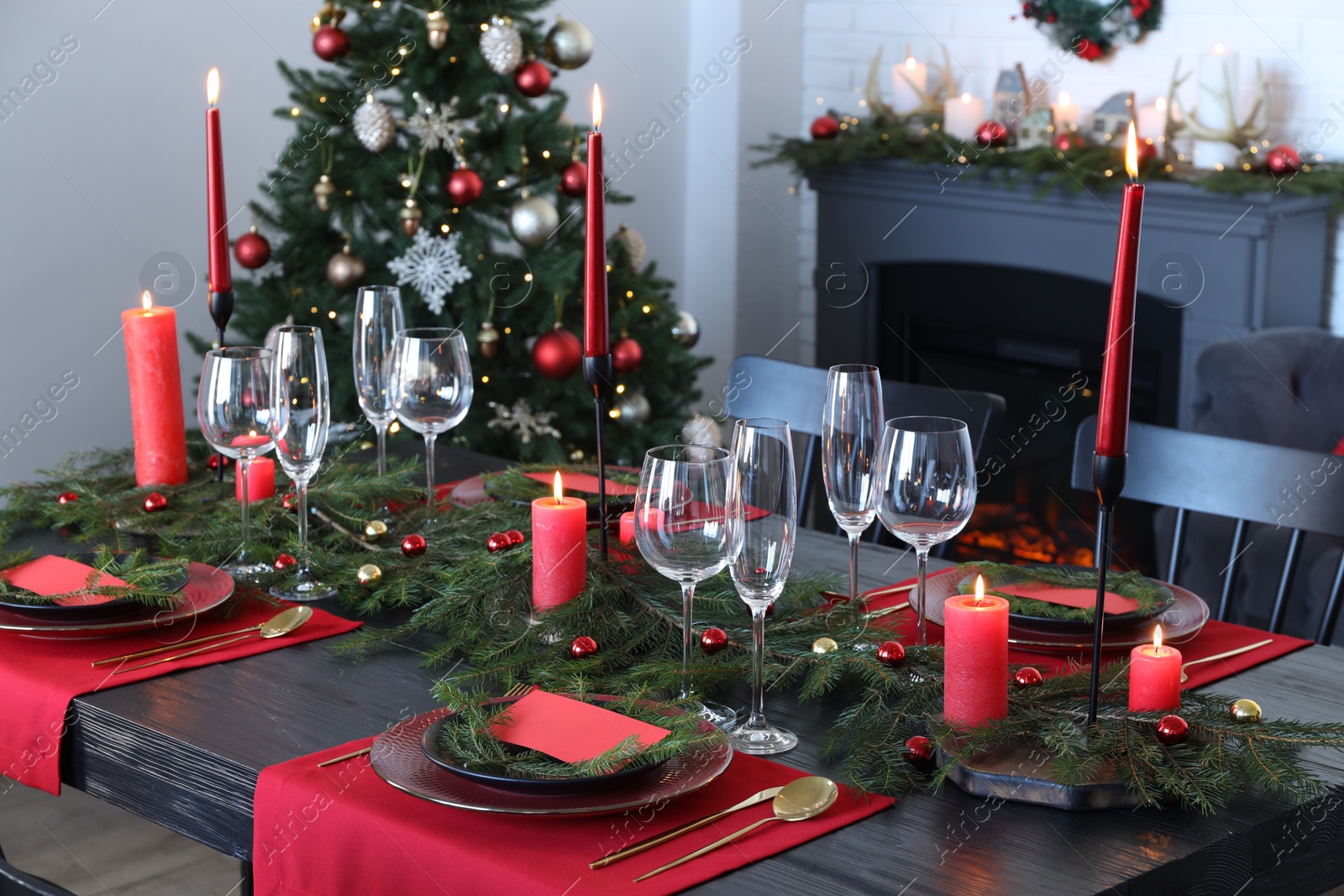 Photo of Elegant Christmas table setting with dishware and burning candles in festively decorated room