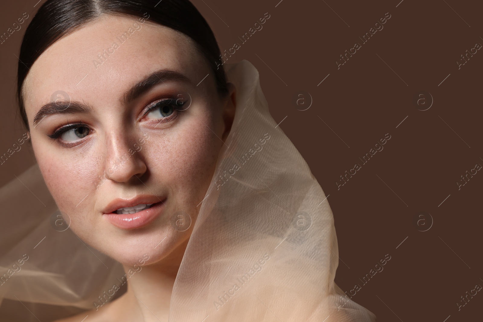 Photo of Fashionable portrait of beautiful woman with fake freckles on brown background. Space for text