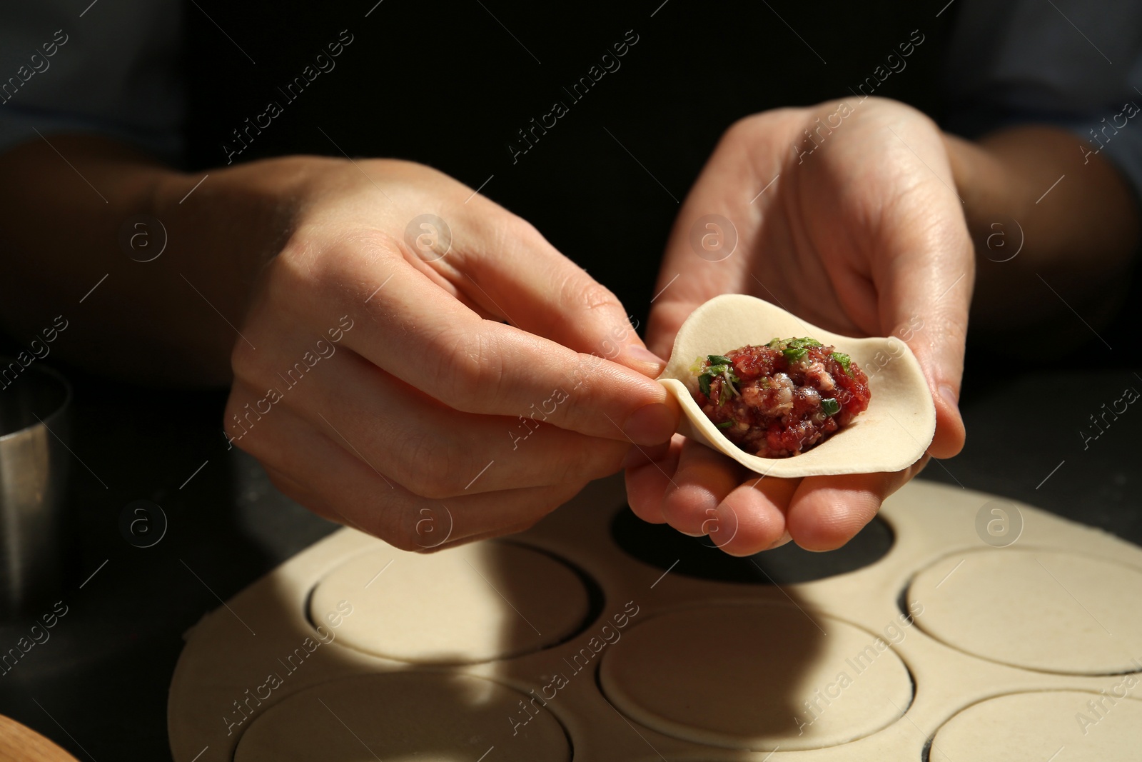 Photo of Woman making gyoza at table, closeup view