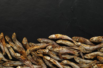 Photo of Delicious dried anchovies on black table, flat lay. Space for text