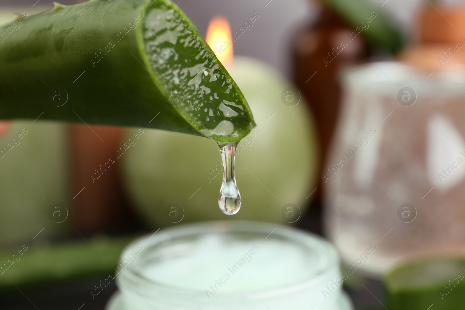Photo of Aloe vera leaf with dripping gel against blurred background, closeup