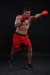 Photo of Man in boxing gloves fighting on black background