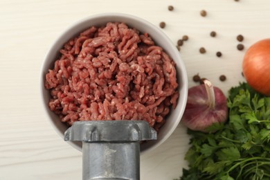 Photo of Mincing beef with meat grinder. Parsley, garlic and peppercorns on white wooden table, flat lay