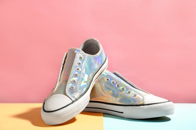 Photo of Pair of stylish sneakers on table against color background