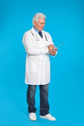 Photo of Senior doctor with clipboard on light blue background