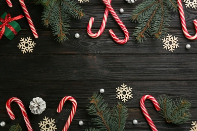Photo of Flat lay composition with candy canes and Christmas decor on black wooden table. Space for text