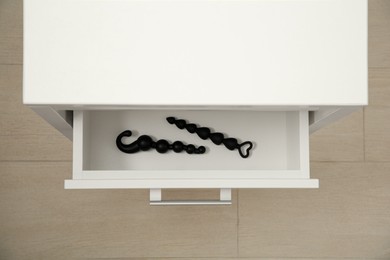 Photo of Black anal beads in drawer indoors, top view. Sex toys