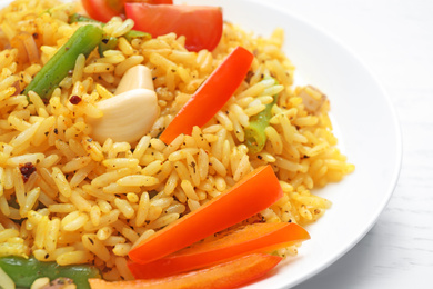 Photo of Tasty rice pilaf with vegetables on white wooden table, closeup