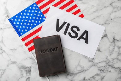 Photo of Flat lay composition with flag of USA, passport and word VISA on marble background