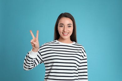 Photo of Woman showing number two with her hand on light blue background