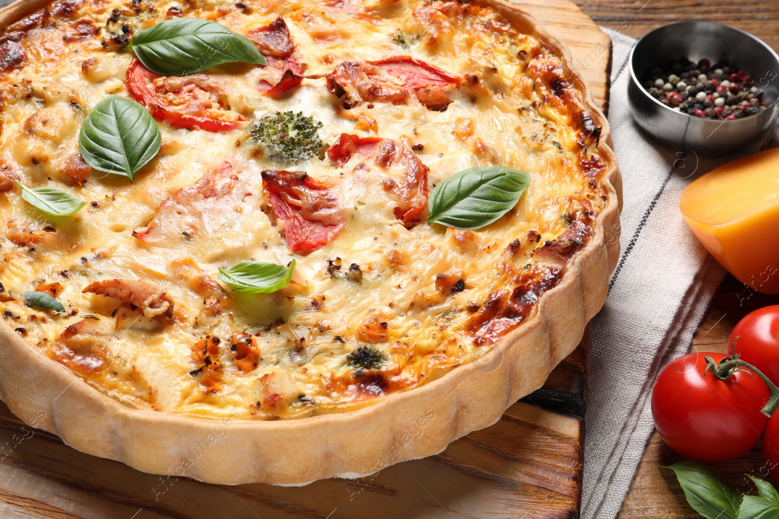 Tasty quiche with tomatoes, basil and cheese served on wooden table, closeup Photo of Tasty quiche with tomatoes, basil and cheese served on wooden table, closeup