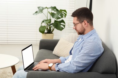 Photo of Man using laptop on couch at home