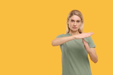 Photo of Woman showing time out gesture on yellow background, space for text. Stop signal