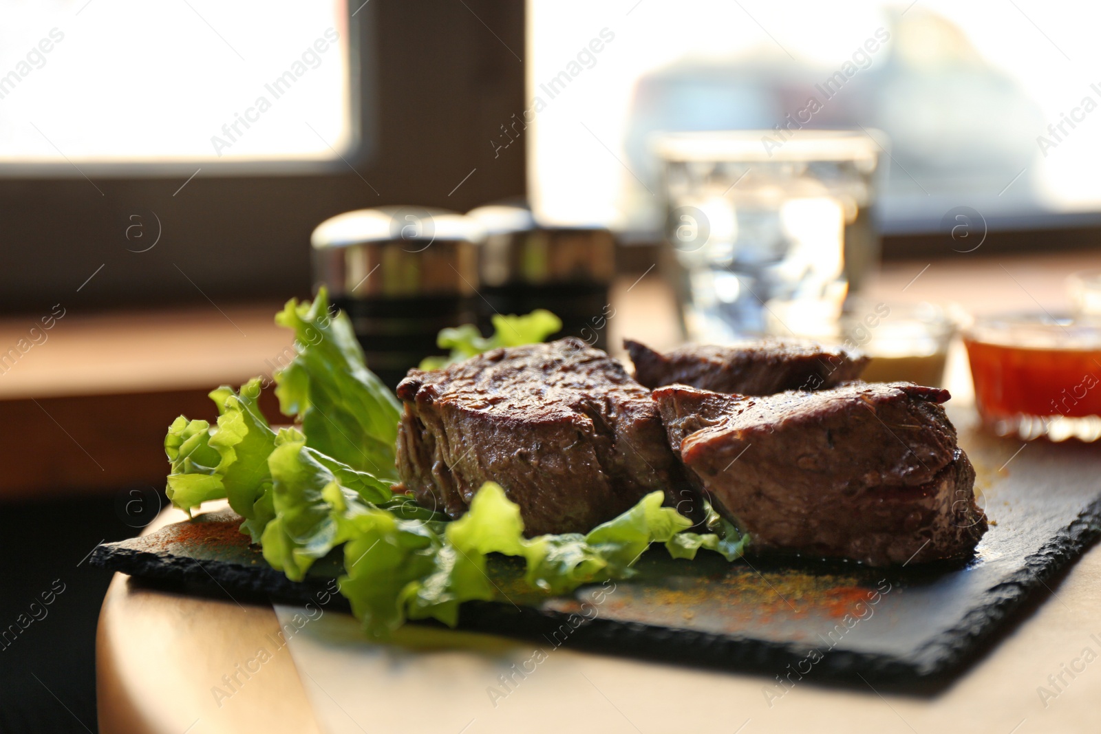 Photo of Tasty pieces of shish kebab served on slate plate in cafe