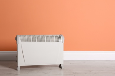 Photo of Modern electric convection heater on floor in room, space for text