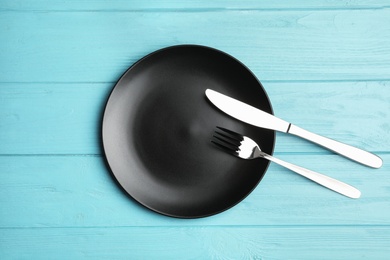 Photo of Stylish ceramic plate and cutlery on wooden background, flat lay