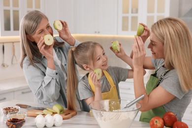 Three generations. Happy grandmother, her daughter and granddaughter having fun while cooking together in kitchen