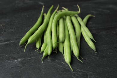 Photo of Fresh green beans on black table, closeup