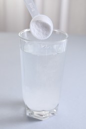 Photo of Adding baking soda into glass of water at white table