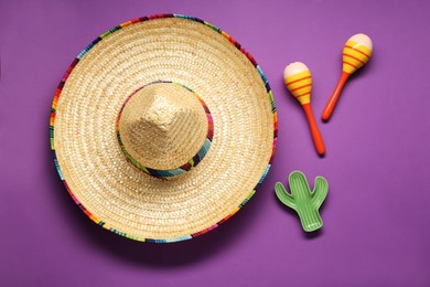 Photo of Mexican sombrero hat, maracas and toy cactus on violet background, flat lay