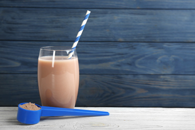 Photo of Protein shake and powder on white wooden table, space for text