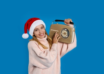 Photo of Happy woman with vintage radio on blue background. Christmas music