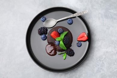 Photo of Plate with delicious chocolate fondant, berries and mint on grey table, top view